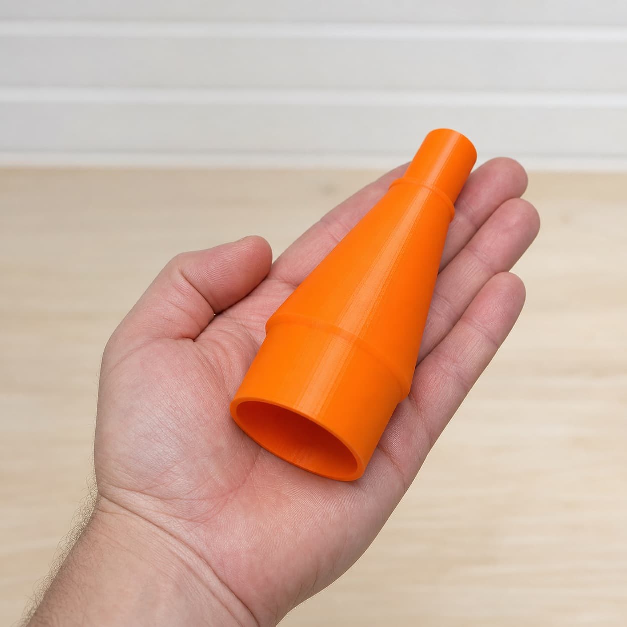 The DBO380 to Craftsman 20G dust adapter held in one hand to show its size
