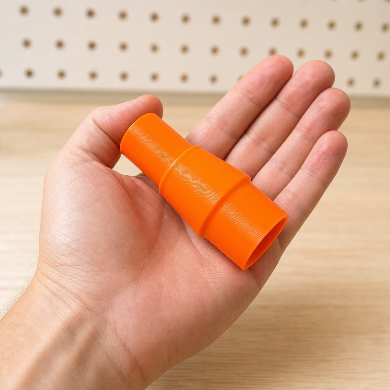 The 9404 to Bosch VAC090AH dust adapter held in one hand to show its size