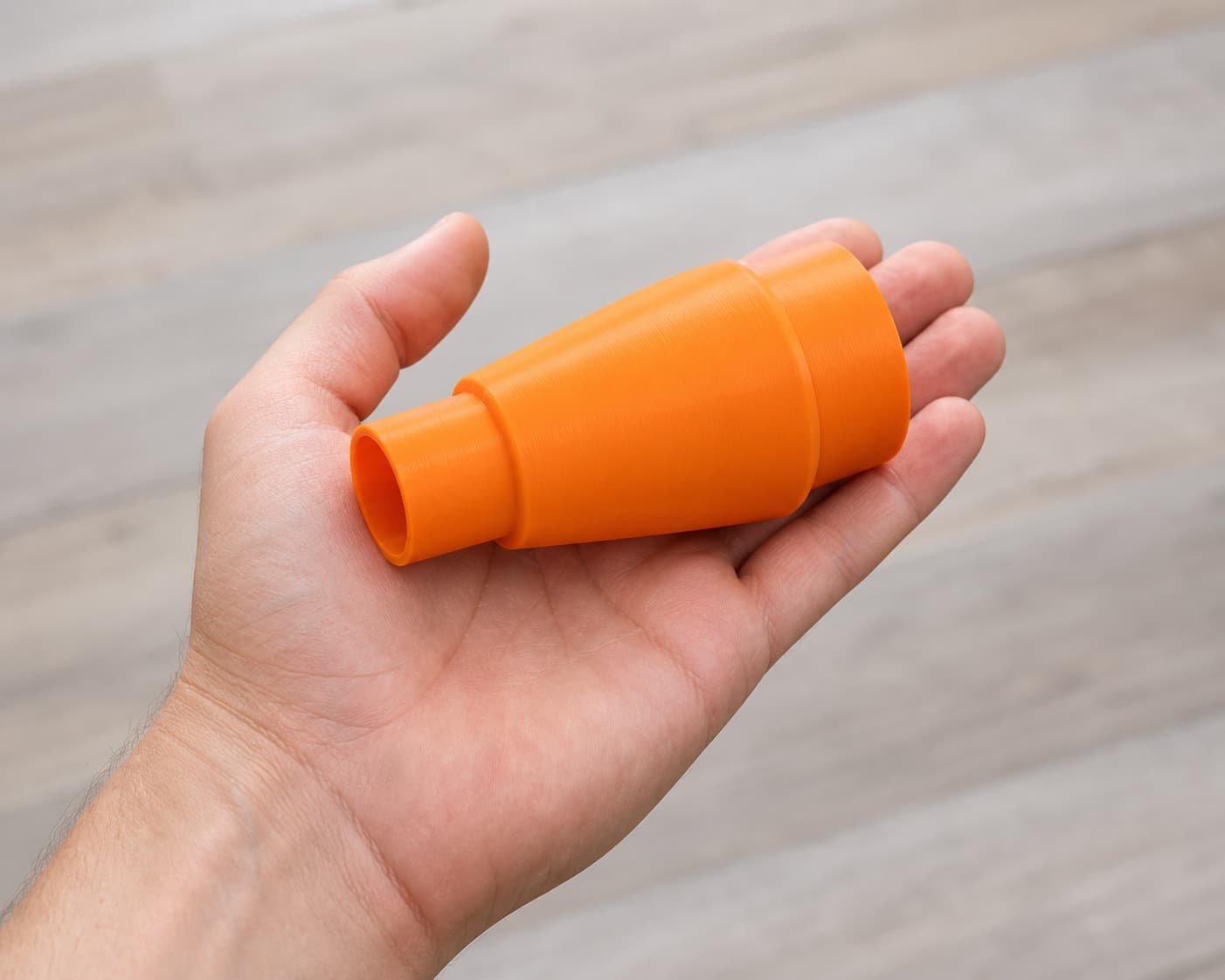 The 2723-20 to Craftsman 16G dust adapter held in one hand to show its size