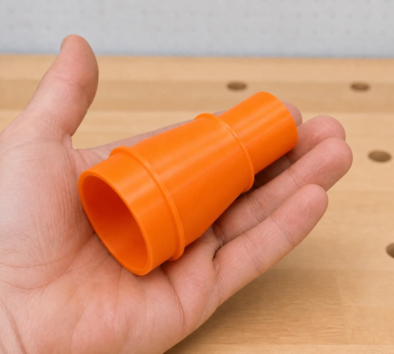 The DCW600B to Craftsman 20G dust adapter held in one hand to show its size