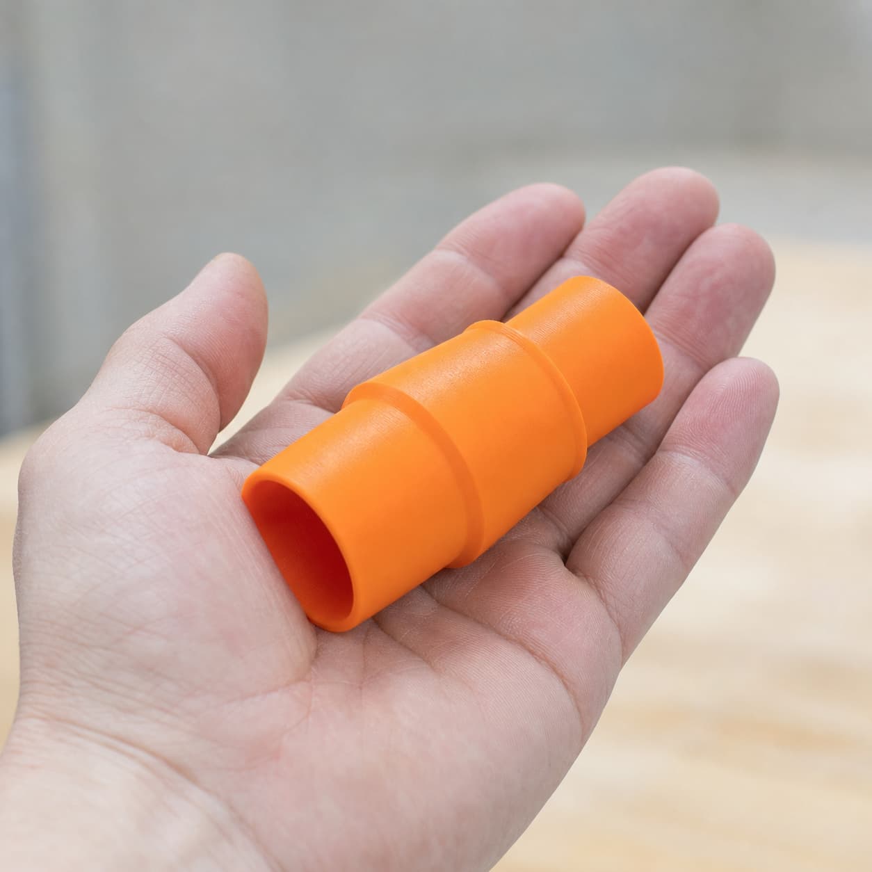 The 2648-20 to Bosch GAS18V-10L dust adapter held in one hand to show its size