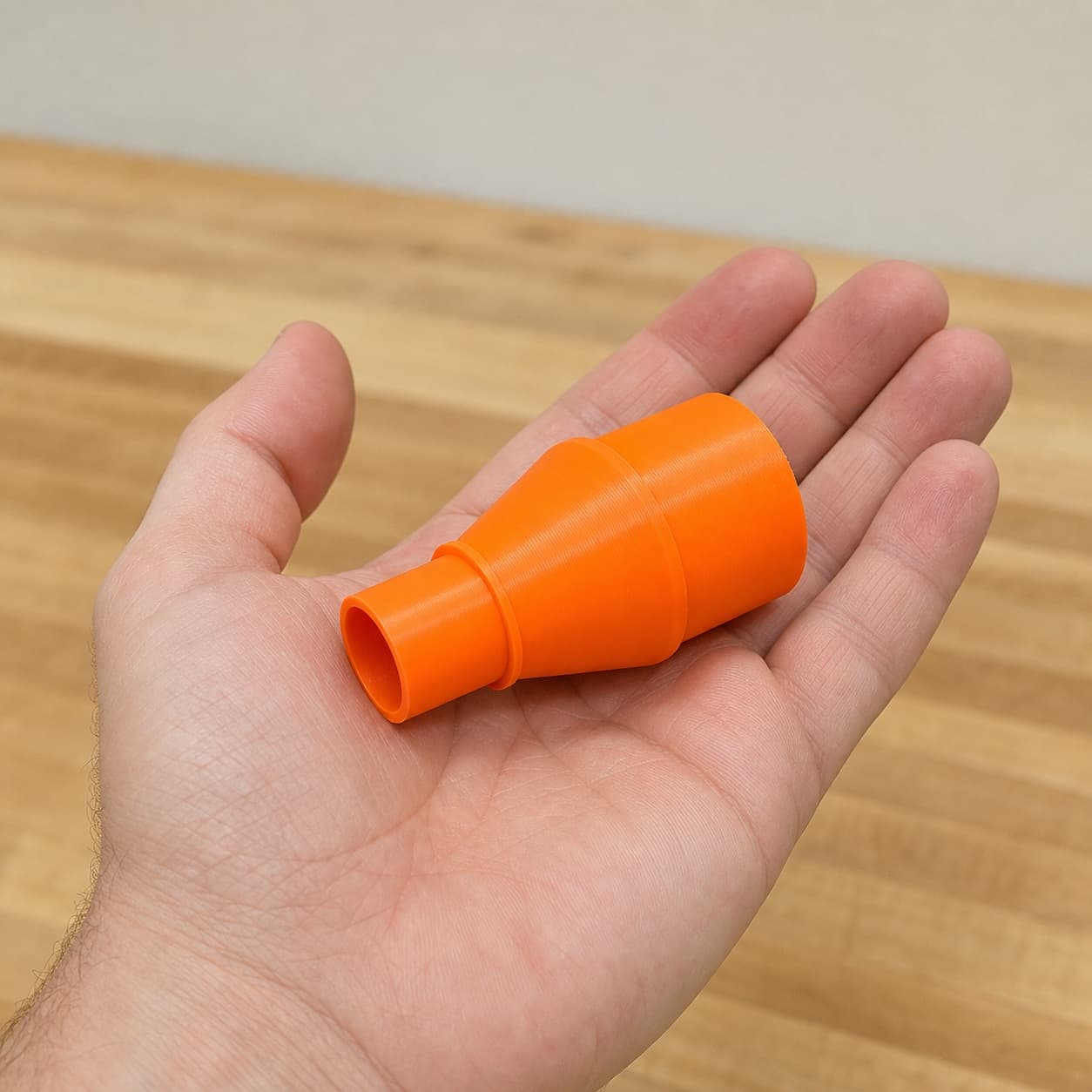 The R8832 to M18 6G Vac dust adapter held in one hand to show its size