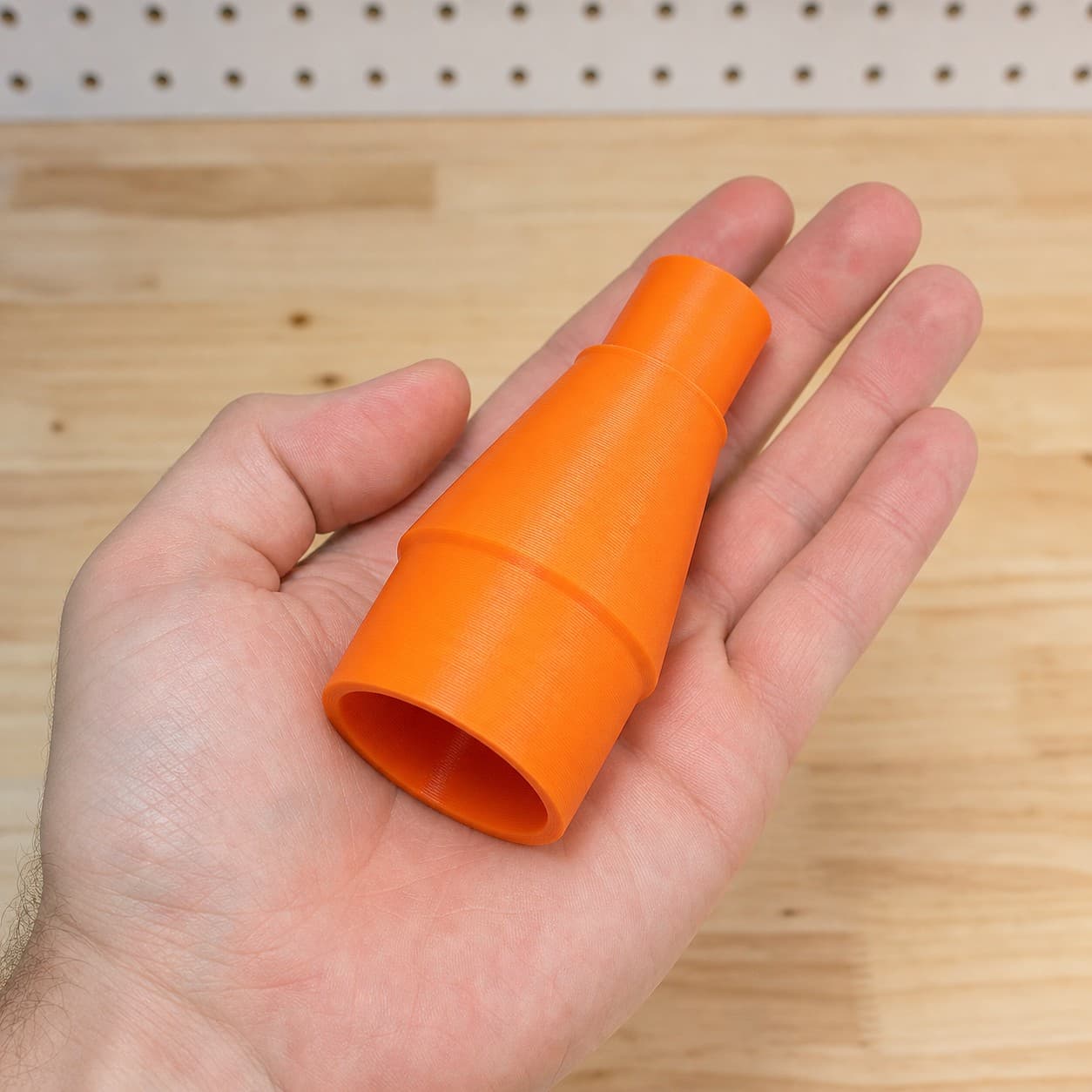 The DRT50 to Craftsman 16G dust adapter held in one hand to show its size