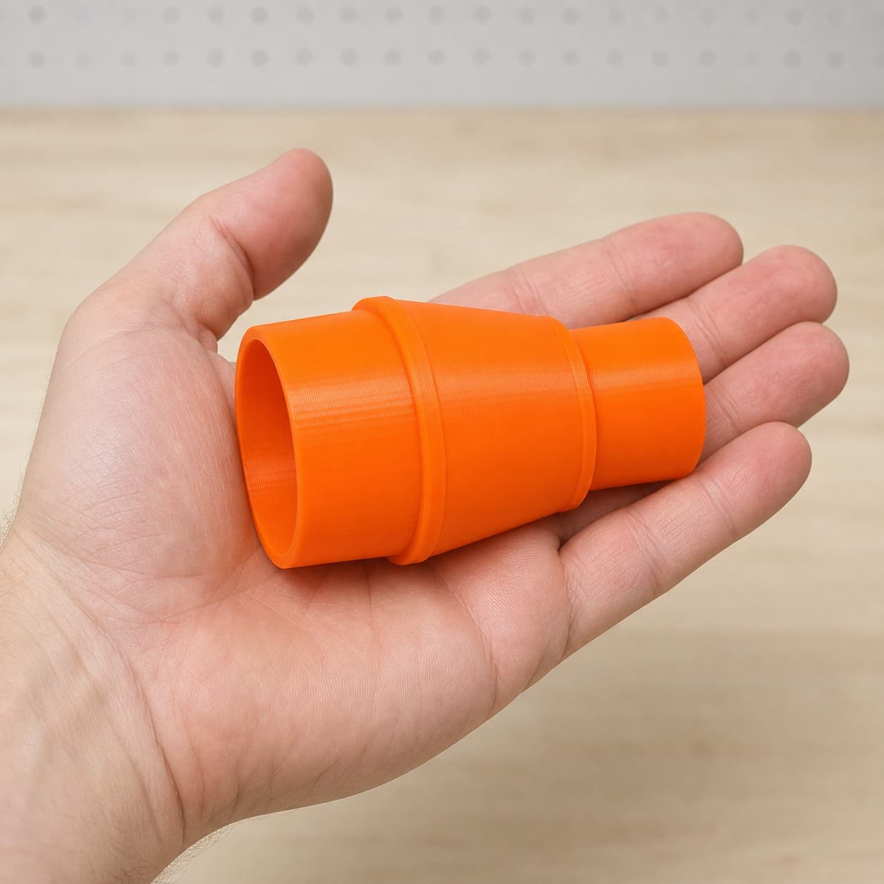 The DWS682K to Craftsman 20G dust adapter held in one hand to show its size