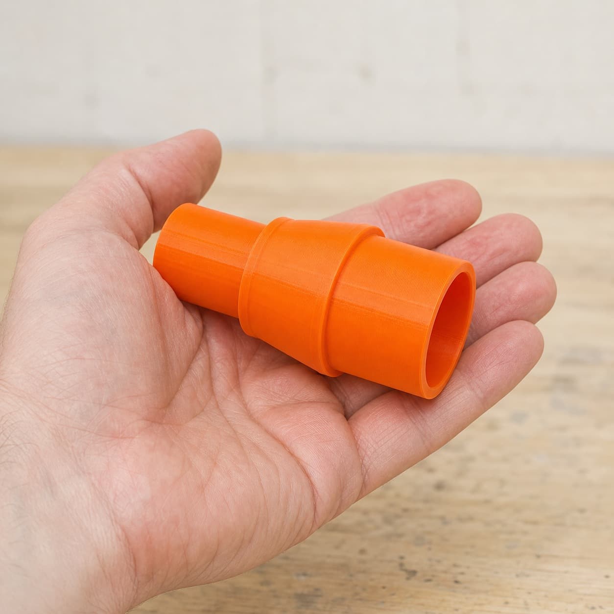 The DWS780 to Festool CT MINI dust adapter held in one hand to show its size