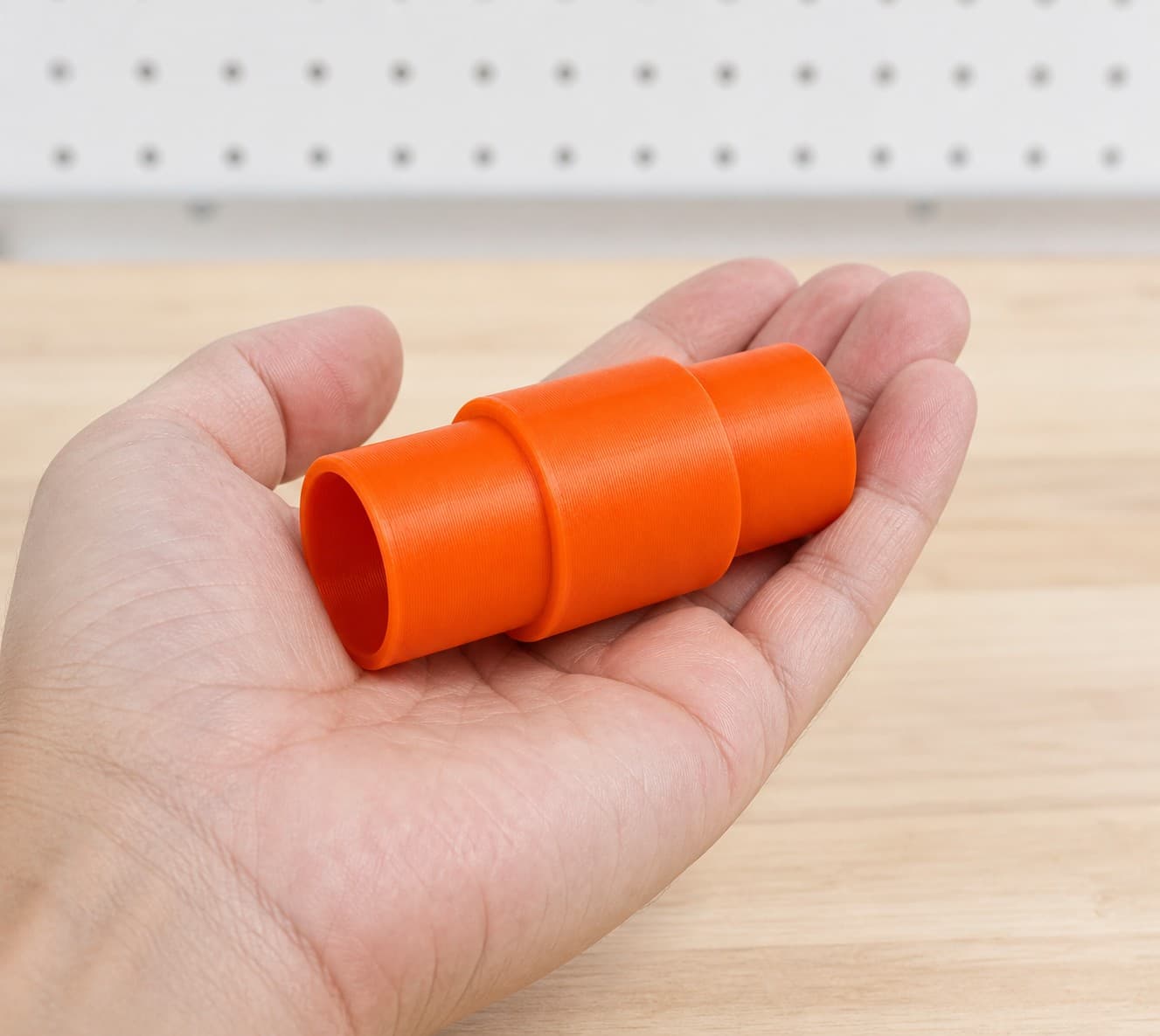 The 352VS to DeWalt DCV517B dust adapter held in one hand to show its size