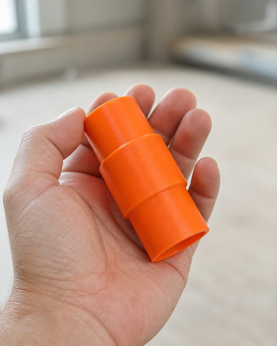 The PTS01 to Bosch GAS18V-3N dust adapter held in one hand to show its size
