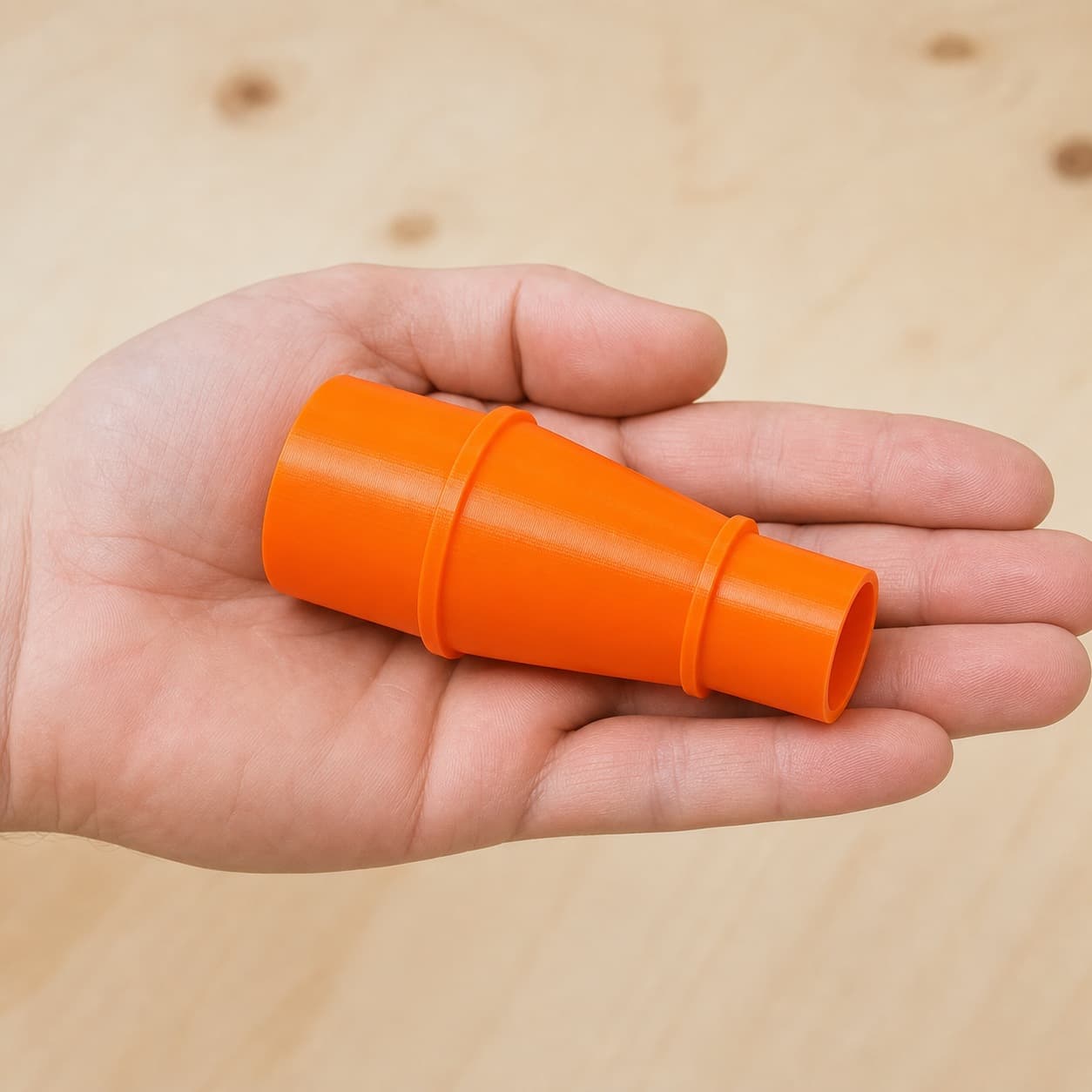 The MultiMaster to 27mm Festool dust adapter held in one hand to show its size