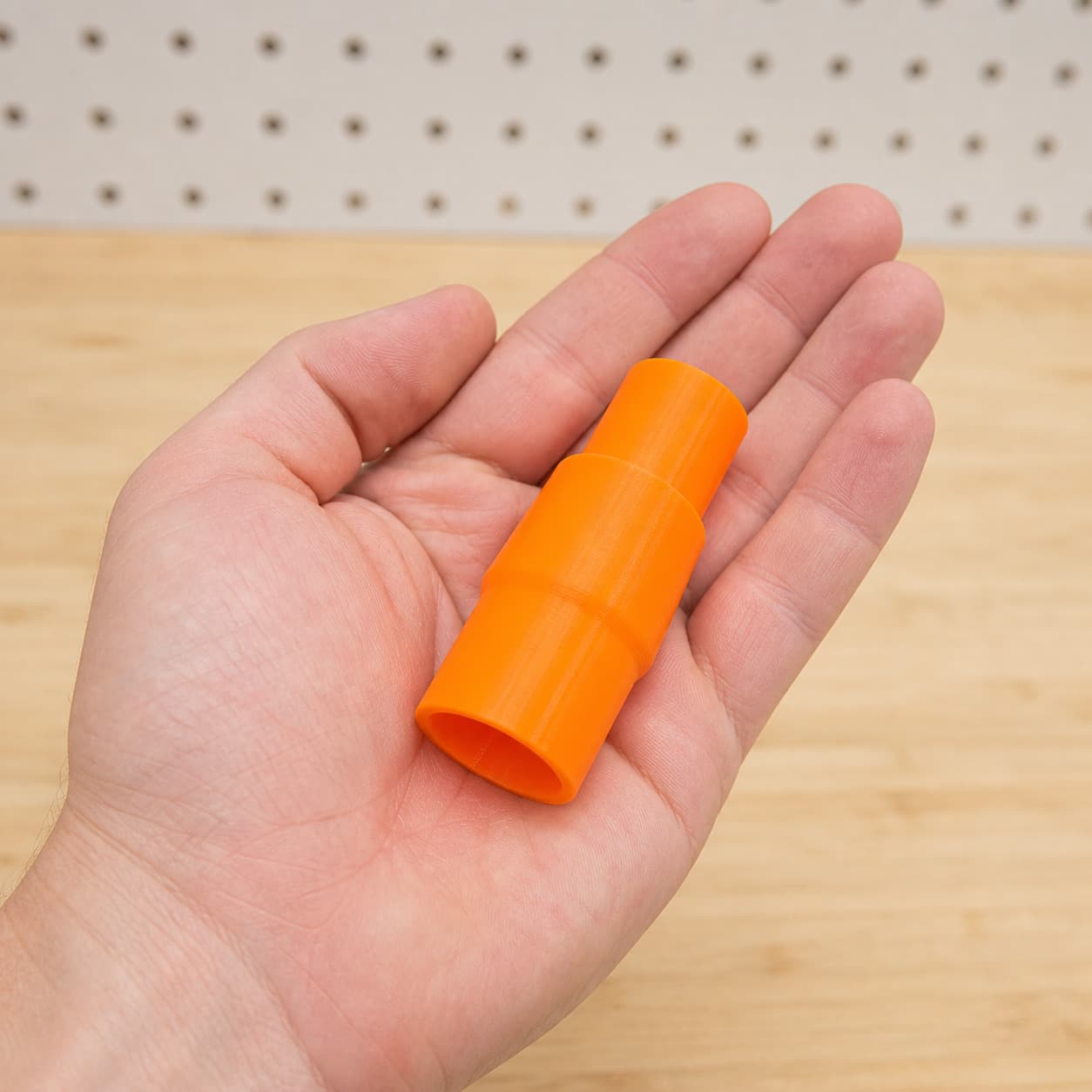 The MultiMaster to DeWalt DCWV201B dust adapter held in one hand to show its size