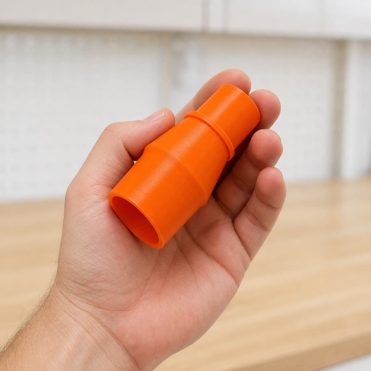 The 69033 to 27mm Festool dust adapter held in one hand to show its size