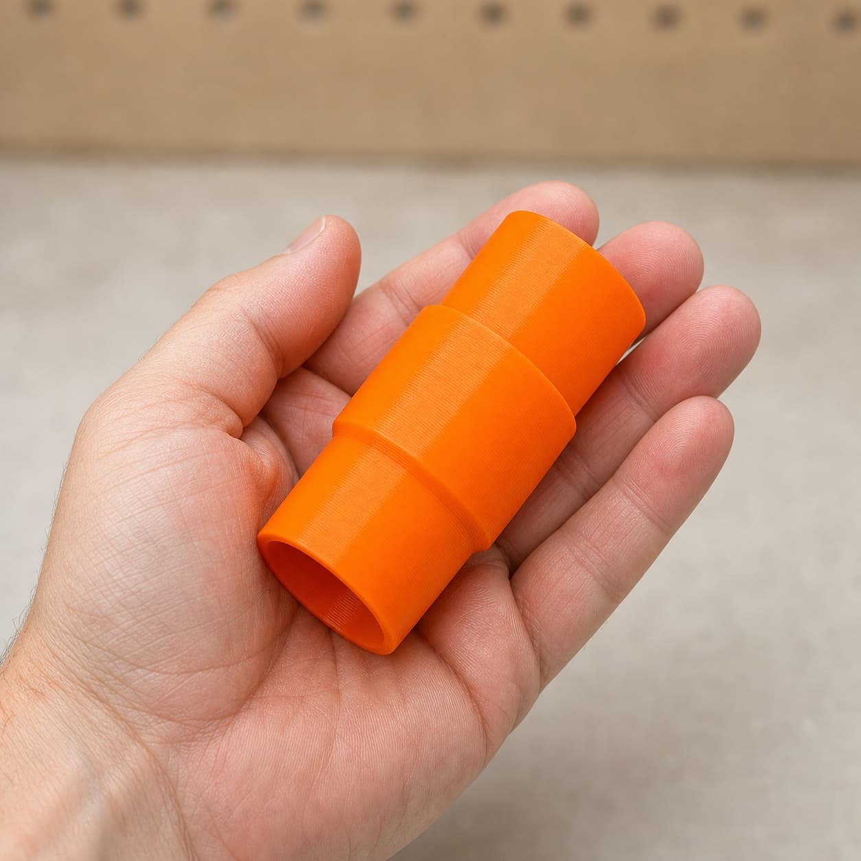The 3386-01 to Bosch GAS18V-10L dust adapter held in one hand to show its size