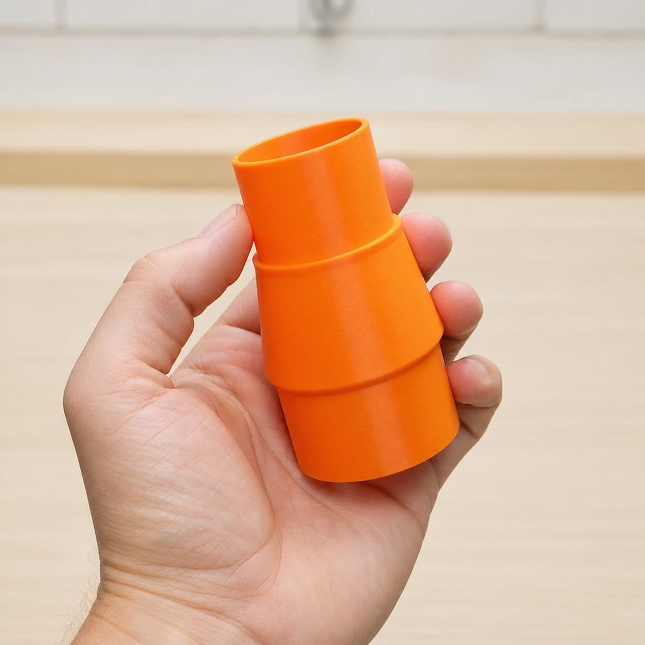 The 3386-01 to M18 6G Vac dust adapter held in one hand to show its size