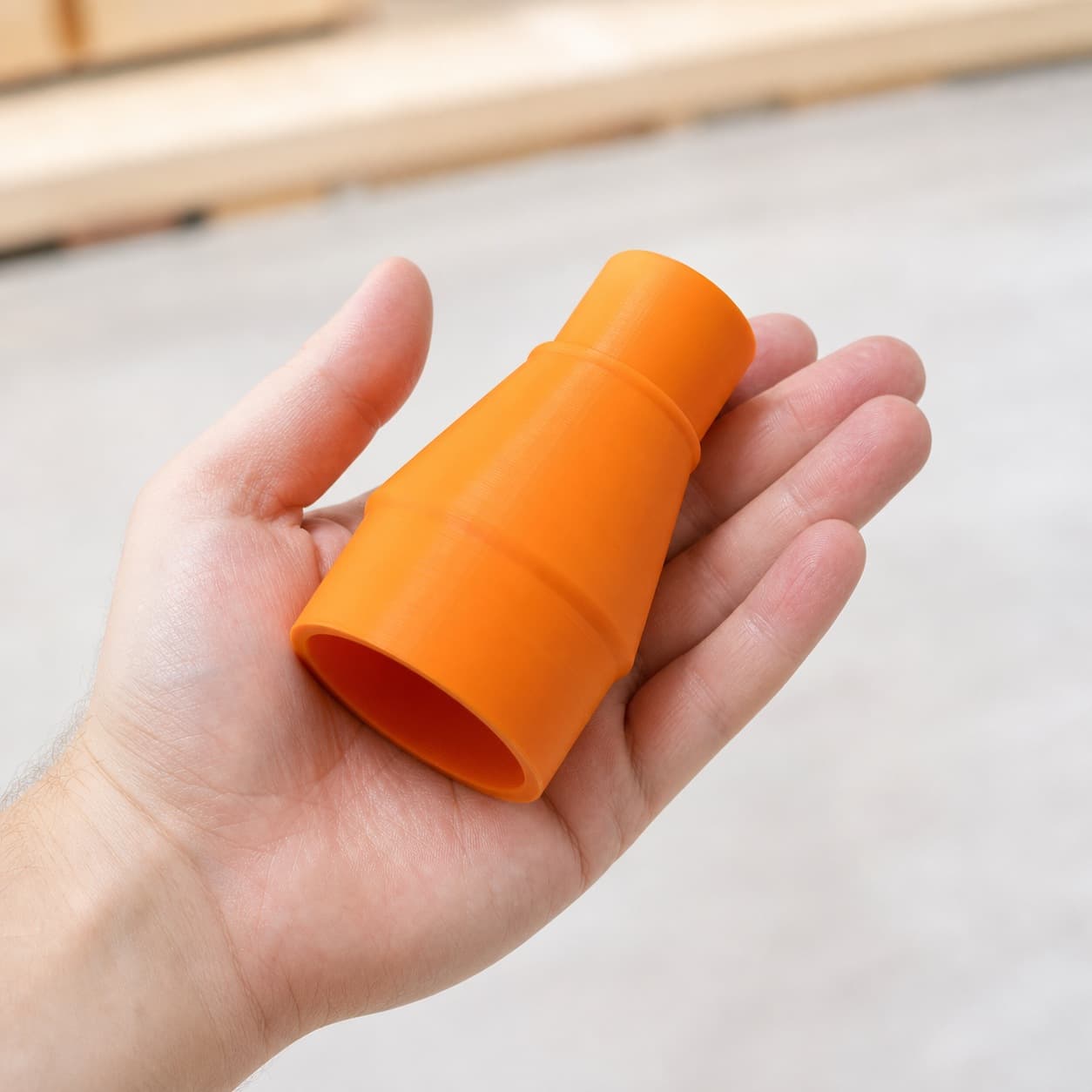 The 3386-01 to Ridgid 14G NXT dust adapter held in one hand to show its size