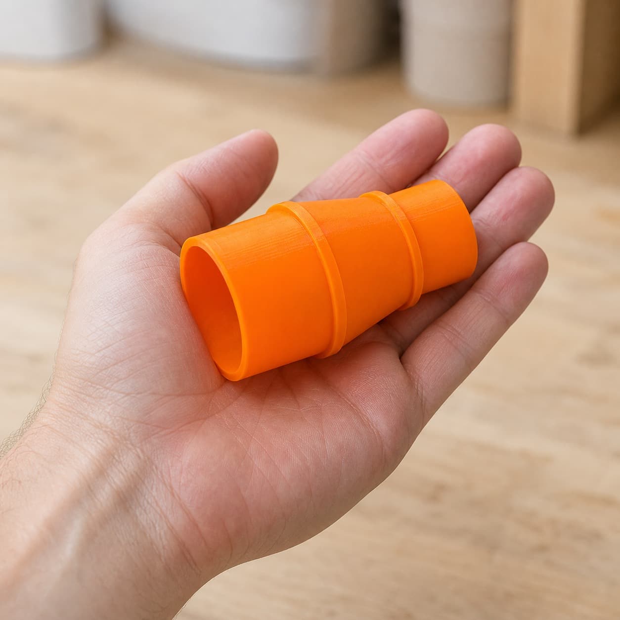 The R8606B to M18 6G Vac dust adapter held in one hand to show its size