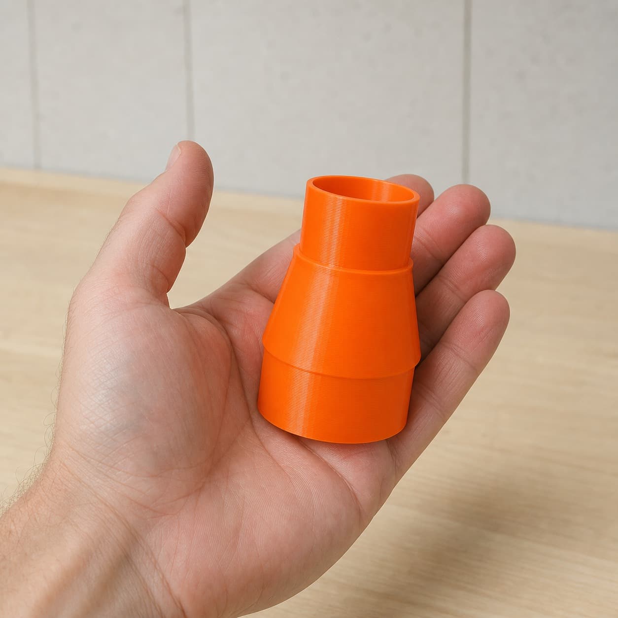 The KGS 216 M to Ridgid 14G NXT dust adapter held in one hand to show its size