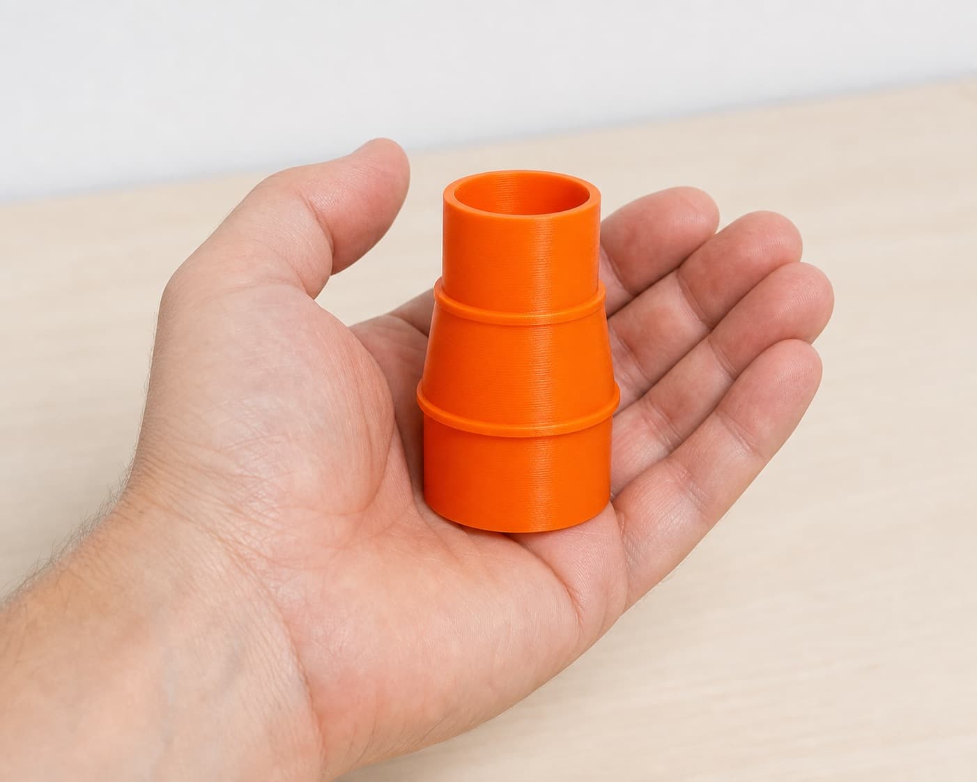 The DCP580B to Craftsman 20G dust adapter held in one hand to show its size
