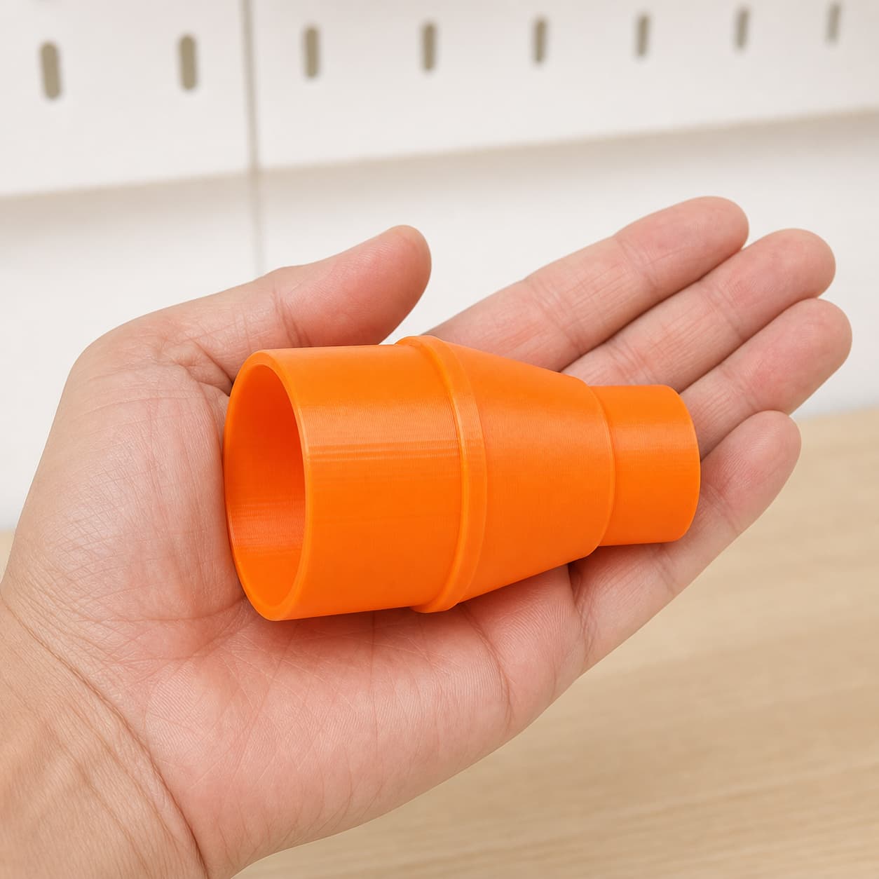 The DWE6423K to Craftsman 16G dust adapter held in one hand to show its size