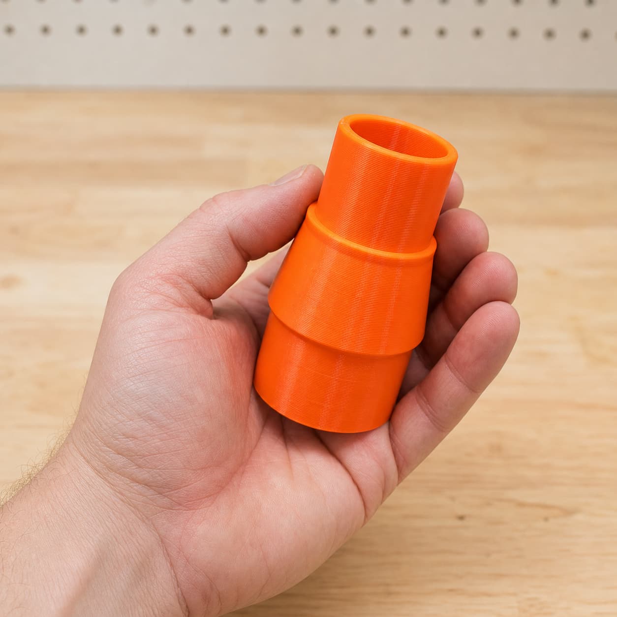 The KP0810 to Bosch GAS18V-10L dust adapter held in one hand to show its size