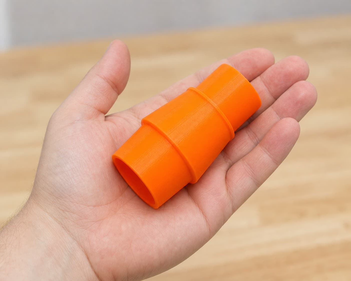 The KP0810 to Makita XCV11Z 2G dust adapter held in one hand to show its size