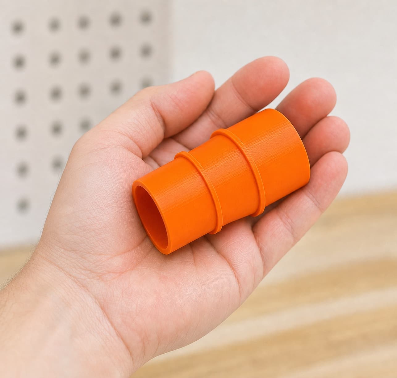 The 58862 to Ridgid 14G NXT dust adapter held in one hand to show its size
