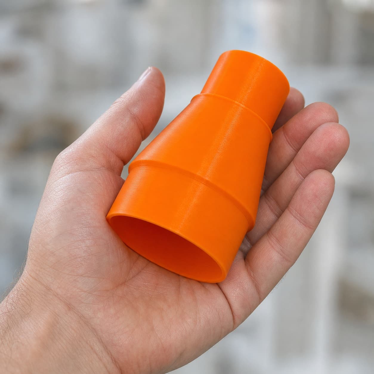 The CMXETAX to Makita XCV11Z 2G dust adapter held in one hand to show its size